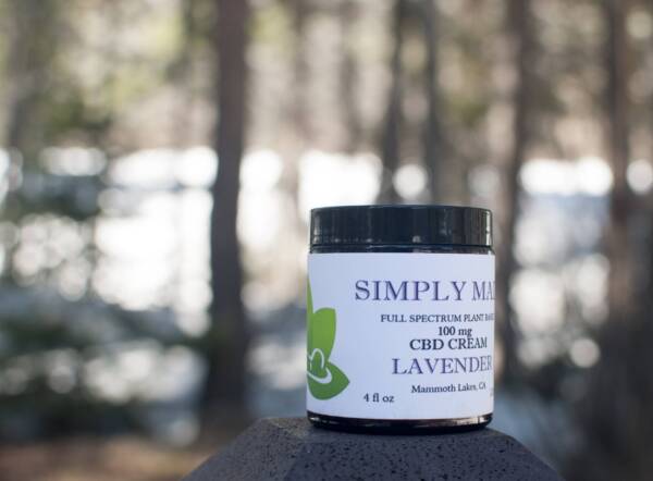 A jar of simply made cbd cream sitting on top of a tree.